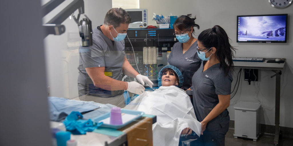 Dr. Silegy in operatory with 2 assistants and elderly female patient receiving all-on-4 dental implants