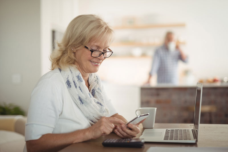 Middle-aged blonde woman holding calculator determining the cost of full mouth dental implants.